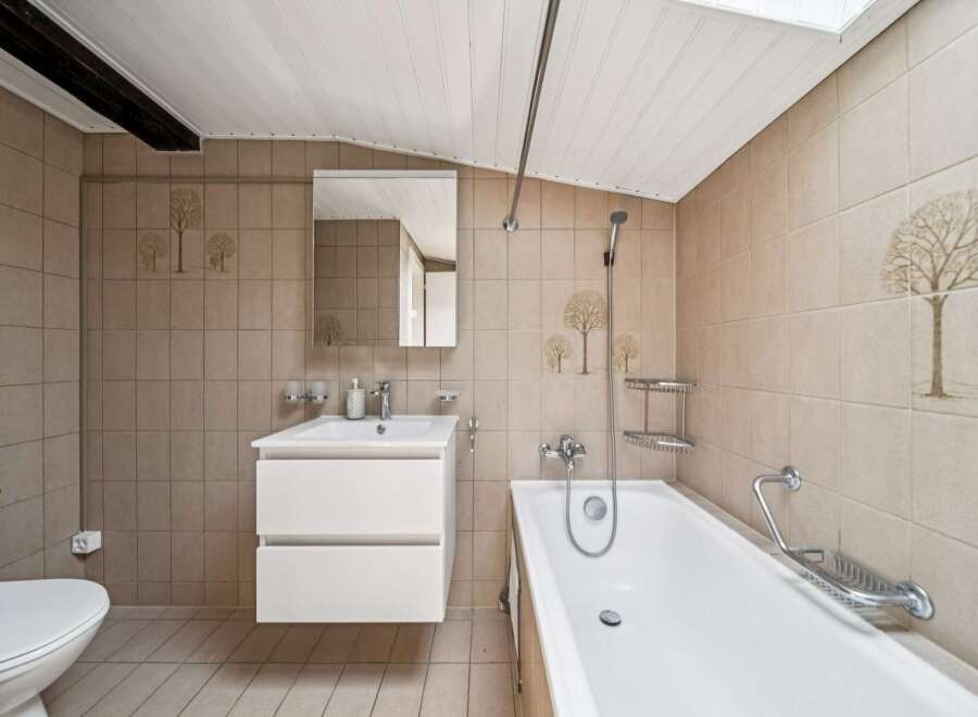 This charming bathroom features a clean white bathtub and a modern vanity with ample storage.