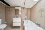 This charming bathroom features a clean white bathtub and a modern vanity with ample storage.