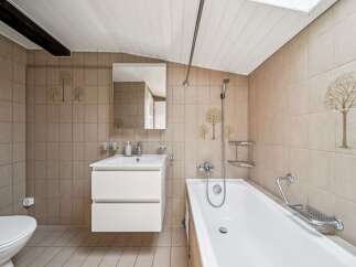This charming bathroom features a clean white bathtub and a modern vanity with ample storage.
