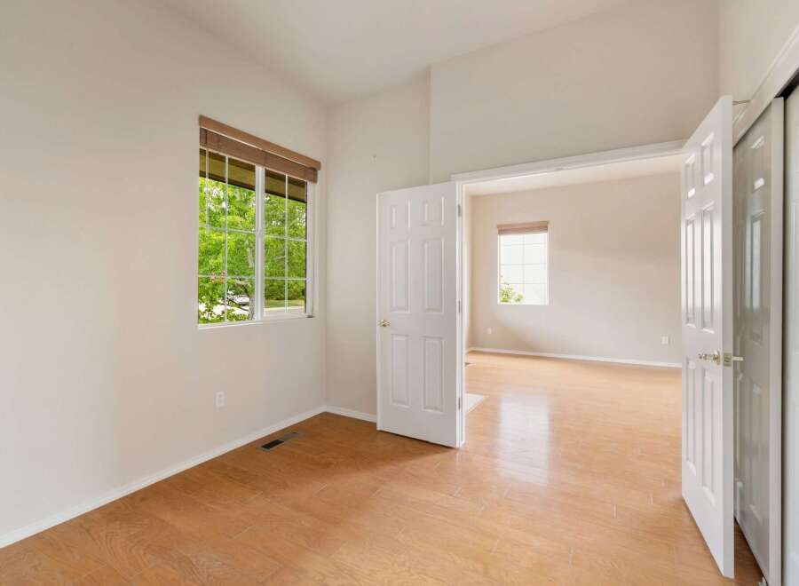 This bright and airy room features a large window with a view of lush greenery, flooding the space with natural light.
