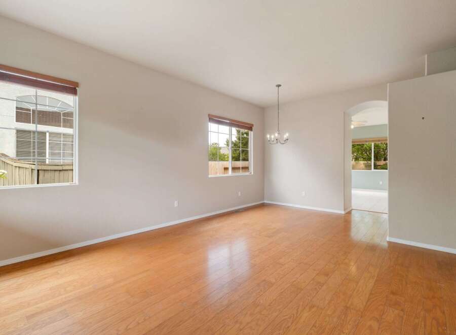 Experience spacious living in this inviting room featuring gleaming hardwood floors and abundant natural light from large windows.