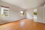 Experience spacious living in this inviting room featuring gleaming hardwood floors and abundant natural light from large windows.