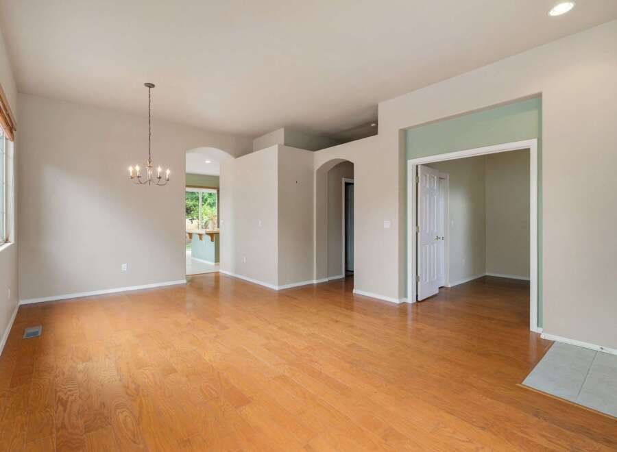 Step into this spacious and inviting living area, featuring gleaming hardwood floors that extend throughout the open-concept layout.