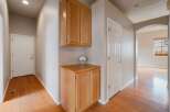This hallway features beautiful hardwood floors that lead to a white door on the left and a set of wooden cabinets on the right.