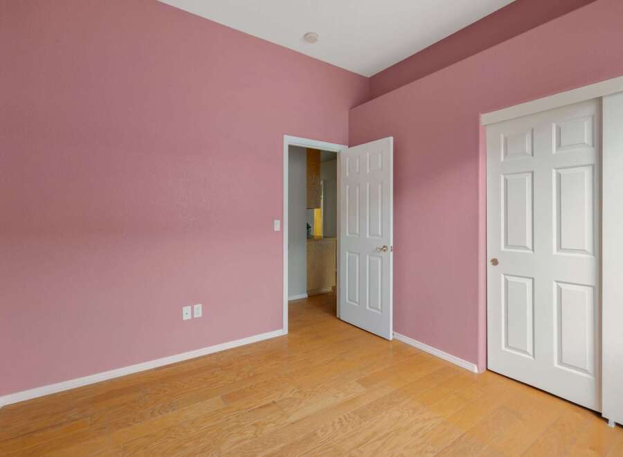Step into this charming room featuring a soft pink accent wall, creating a warm and inviting atmosphere.