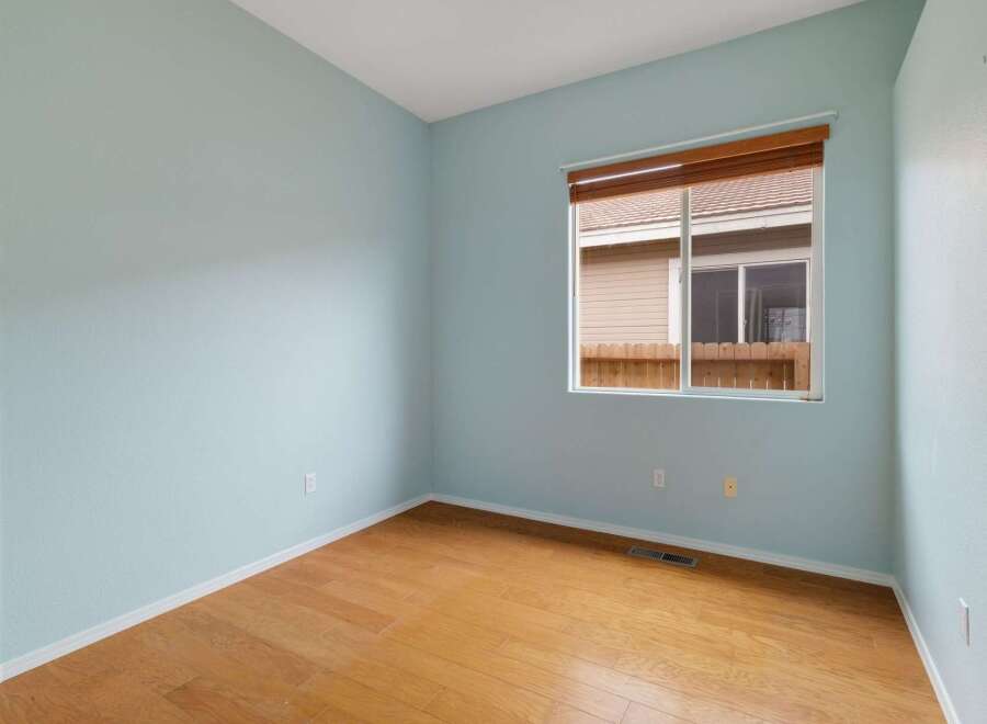 This empty room features light blue walls and a beautiful hardwood floor, creating a bright and airy atmosphere.