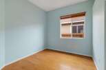 This empty room features light blue walls and a beautiful hardwood floor, creating a bright and airy atmosphere.