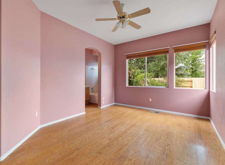 Experience comfort and style in this charming room featuring soft pink walls and gleaming hardwood floors.