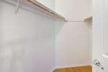 Step into this spacious walk-in closet, featuring a sturdy wooden rod and ample shelving for all your storage needs.