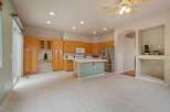 This spacious kitchen features ample natural light, complemented by warm oak cabinetry and a central island with a light green base.