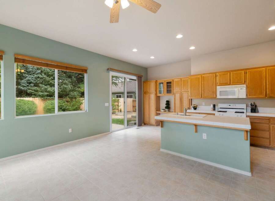 This spacious kitchen features light wood cabinetry, a white tiled countertop, and a central island with a light blue base.