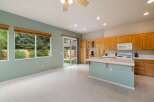 This spacious kitchen features light wood cabinetry, a white tiled countertop, and a central island with a light blue base.