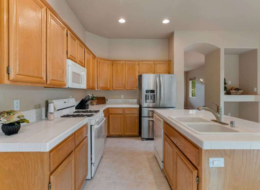 This spacious kitchen features beautiful light wood cabinetry and a large stainless steel refrigerator.