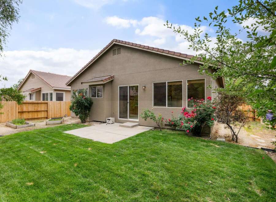Enjoy outdoor living in this charming backyard featuring a lush green lawn and a concrete patio perfect for entertaining.