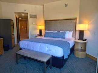 Experience ultimate comfort in this beautifully appointed hotel room, featuring a plush king-sized bed adorned with crisp white linens and a stylish blue accent throw.