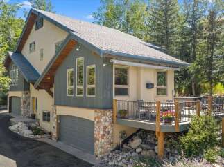 Discover this stunning mountain home featuring a multi-level design with a stone-accented facade and a spacious wooden deck perfect for outdoor entertaining.