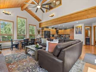 Experience rustic charm in this spacious living area, featuring a vaulted wood-beamed ceiling and a large ceiling fan.