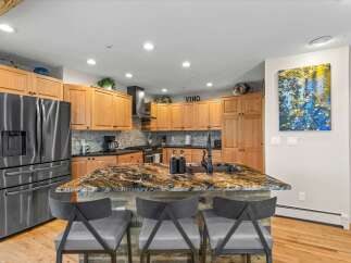 Experience luxury in this stunning kitchen, featuring a dramatic granite island with a waterfall edge and a deep farmhouse sink.