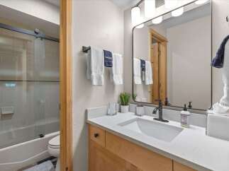 This modern bathroom features a sleek vanity with a white quartz countertop and a deep undermount sink, complemented by a dark bronze faucet.