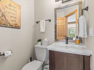 Charming bathroom featuring a rustic wooden vanity and a stone-accented mirror.