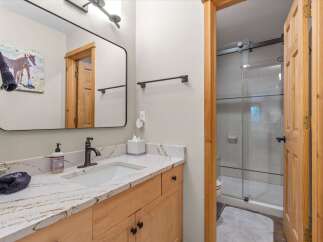 This charming bathroom features a light wood vanity with a stunning marble countertop, complemented by a sleek black faucet and a deep white sink.