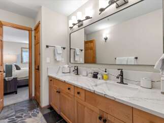 This spacious bathroom features a double vanity with a stunning marble countertop and modern black fixtures.