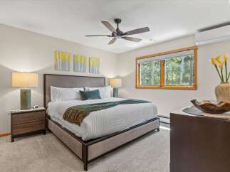 Experience ultimate comfort in this beautifully appointed bedroom, featuring a plush king-size bed adorned with crisp white linens and a cozy green throw.