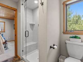 Experience modern comfort in this beautifully appointed bathroom, featuring a sleek glass-enclosed shower with a built-in bench and elegant tilework.