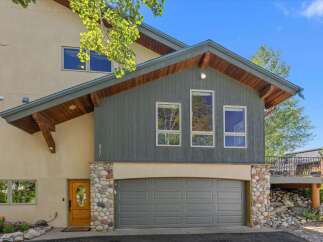 Discover this charming mountain home featuring a striking stone-accented facade and a welcoming wooden front door.