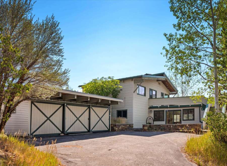 Discover this charming home featuring a distinctive barn-style garage with large double doors, perfect for vehicle storage or a workshop.