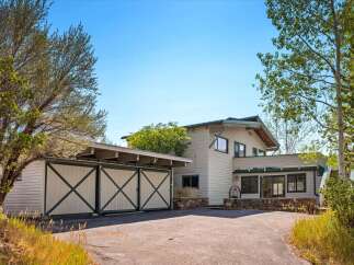 Discover this charming home featuring a distinctive barn-style garage with large double doors, perfect for vehicle storage or a workshop.