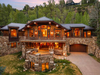 Experience luxury mountain living in this stunning log and stone estate, nestled amidst lush greenery.