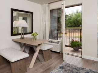 Enjoy the fresh air and natural light from this charming room featuring a cozy seating area with a modern desk and benches.