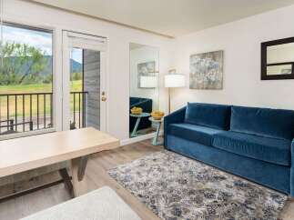 Experience comfort and style in this inviting living space, featuring a plush blue velvet sofa perfect for relaxation.