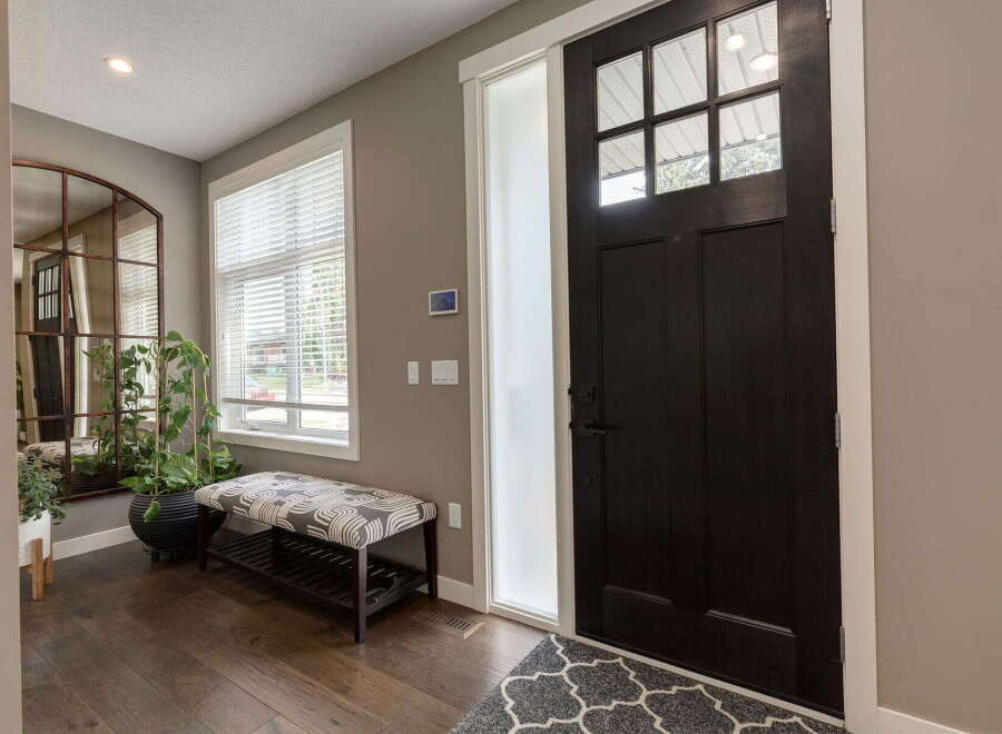 Step into this welcoming entryway featuring a stylish dark wood door with glass panes, complemented by a frosted glass sidelight.