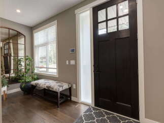 Step into this welcoming entryway featuring a stylish dark wood door with glass panes, complemented by a frosted glass sidelight.