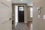 Step into this welcoming entryway featuring a stylish dark wood front door with a multi-pane window, complemented by a frosted glass sidelight.