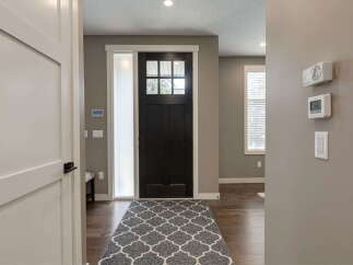 Step into this welcoming entryway featuring a stylish dark wood front door with a multi-pane window, complemented by a frosted glass sidelight.