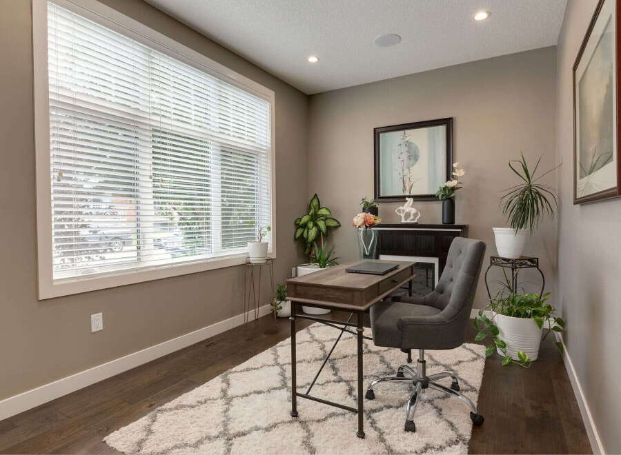 This home office features a large window with blinds, allowing natural light to fill the space.