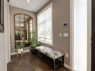 Welcome guests into this inviting entryway featuring a large arched mirror with a rustic metal frame, perfect for last-minute touch-ups.
