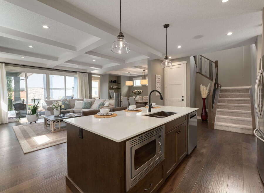 Experience modern living in this open-concept home featuring a gourmet kitchen with a large island, sleek cabinetry, and a built-in microwave.