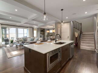 Experience modern living in this open-concept home featuring a gourmet kitchen with a large island, sleek cabinetry, and a built-in microwave.