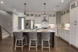 Experience modern luxury in this stunning kitchen, featuring sleek white cabinetry, a spacious island with bar seating, and a professional-grade stainless steel range hood.