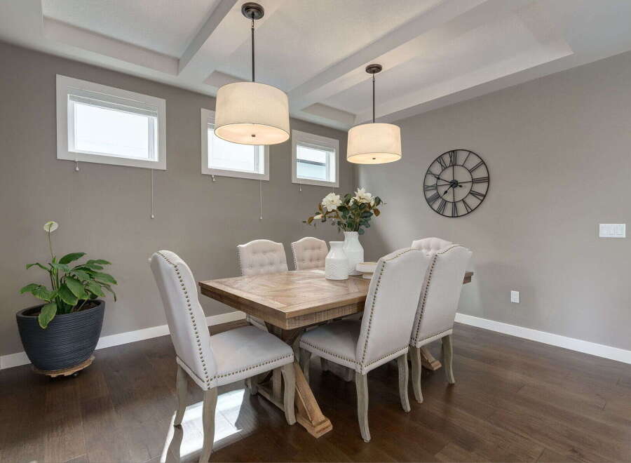 This elegant dining room features a rustic wooden table surrounded by upholstered chairs with nailhead trim.