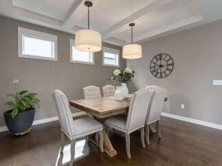 This elegant dining room features a rustic wooden table surrounded by upholstered chairs with nailhead trim.