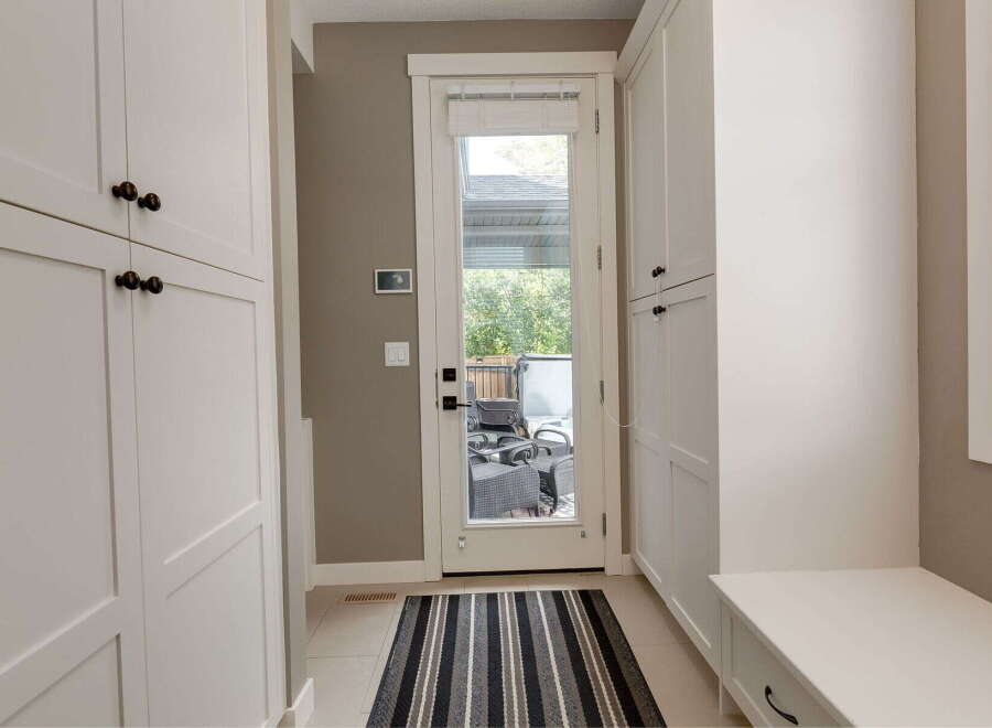 Step into this inviting entryway featuring ample storage with floor-to-ceiling white cabinets and a convenient built-in bench.