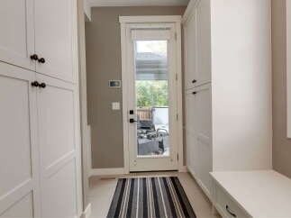 Step into this inviting entryway featuring ample storage with floor-to-ceiling white cabinets and a convenient built-in bench.