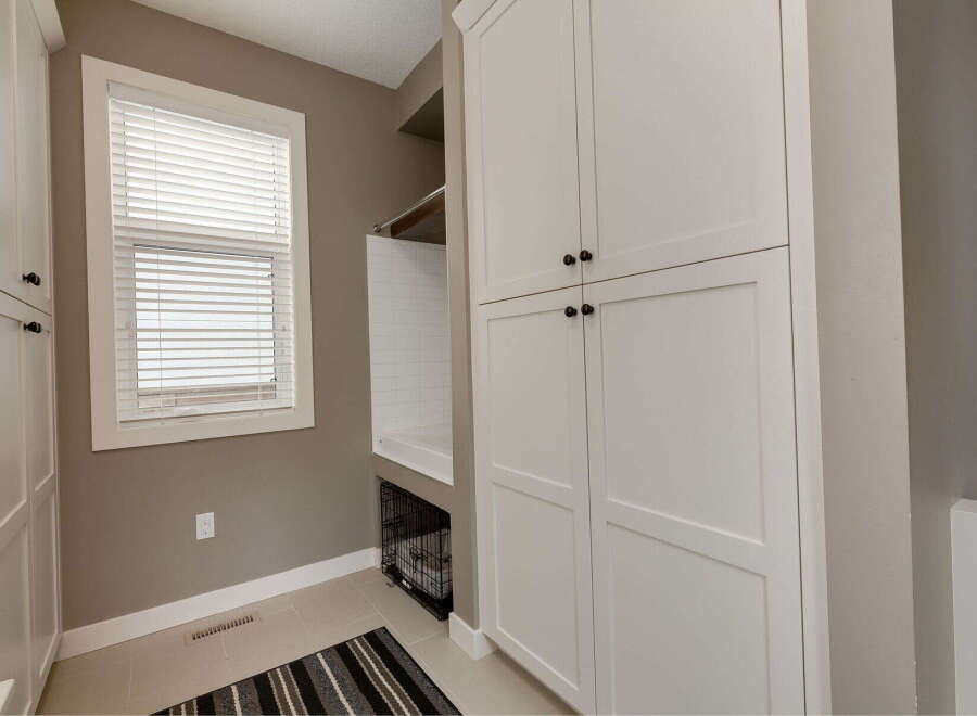This laundry room features ample storage with tall white cabinets and a built-in dog washing station.