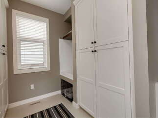 This laundry room features ample storage with tall white cabinets and a built-in dog washing station.