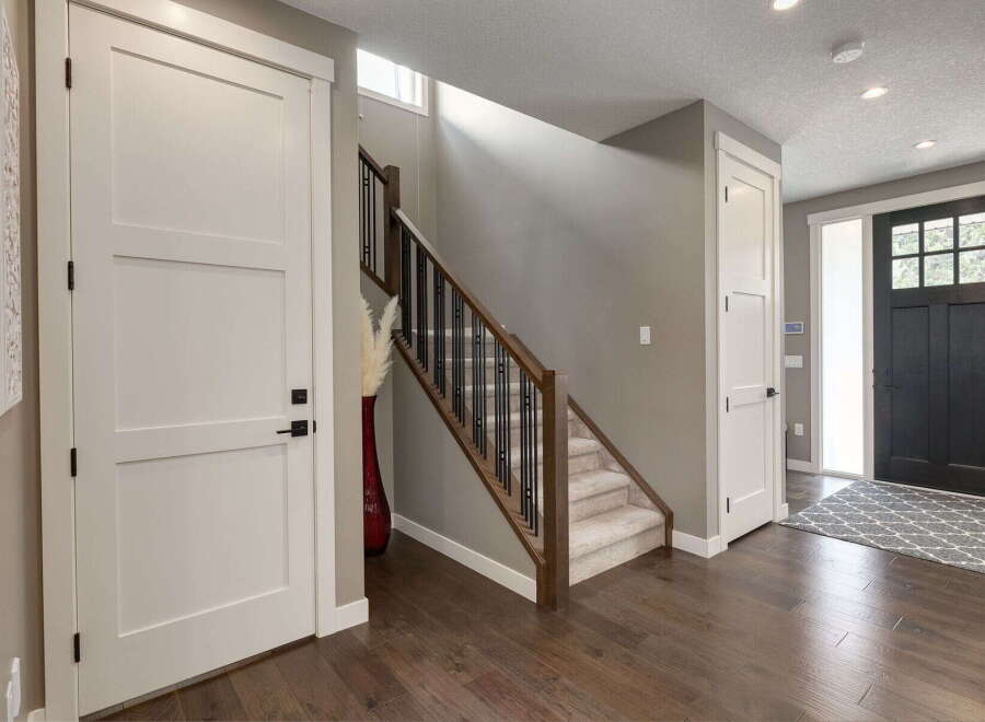Step into this inviting entryway featuring a modern staircase with dark wood railings and sleek black spindles.